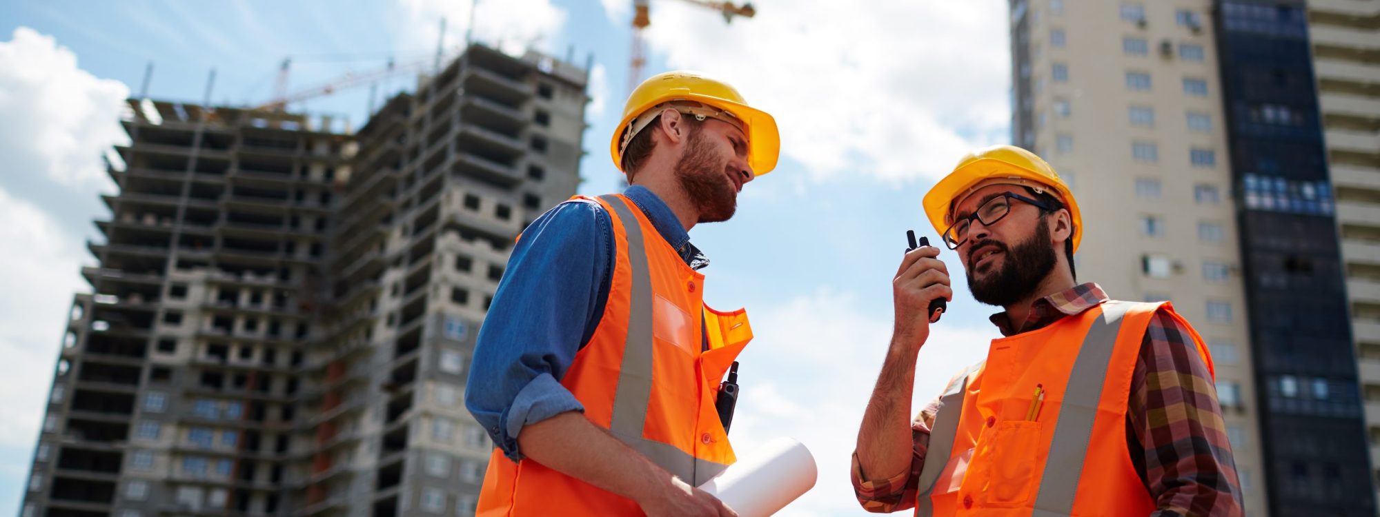 Contractor speaking on walkie-talkie with co-worker near by